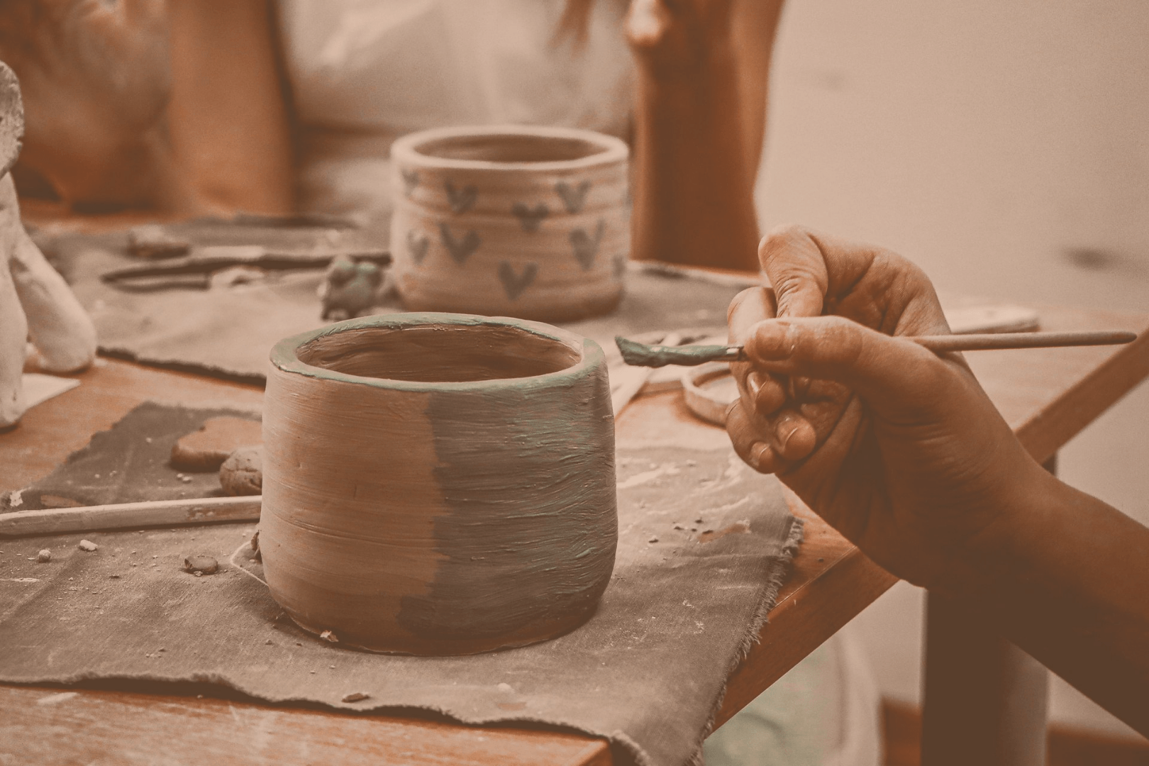 Two pottery cups being decorated with paint