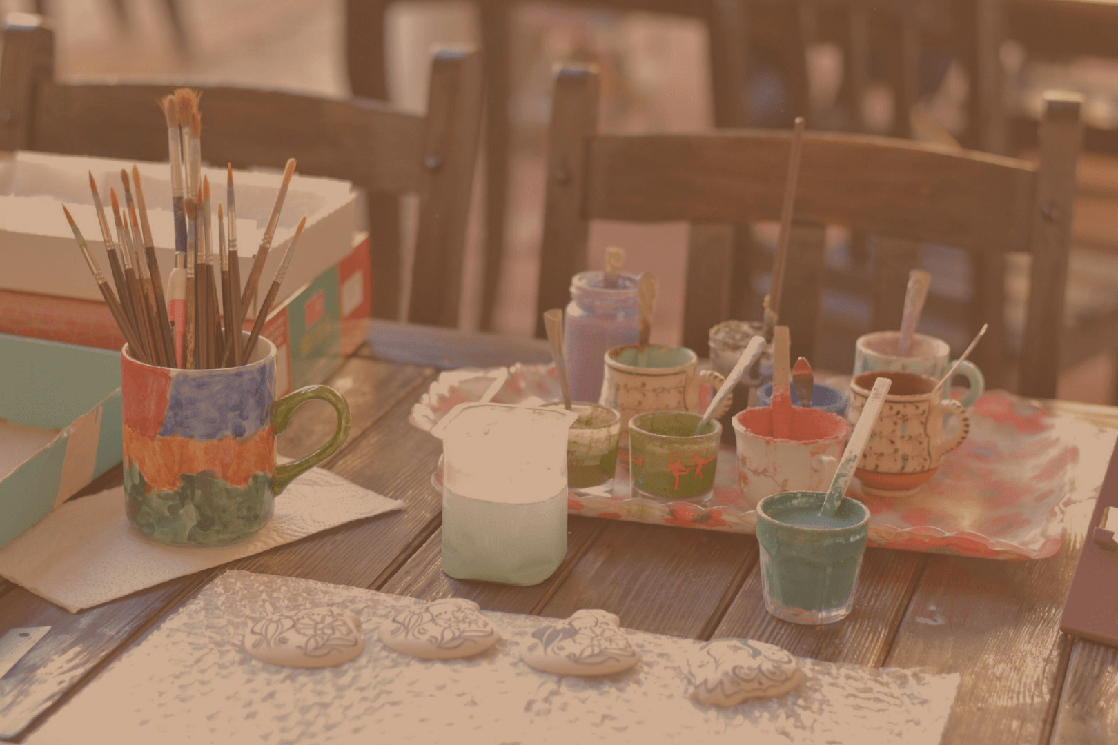 Variety of colored paints and paintbrushes being used to paint boho designs on rocks.